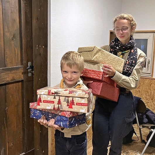 Alle Wölflinge und Pfadfinder packen gemeinsam die Pakete Die Pfadfinder haben fertige Päckchen in den Händen